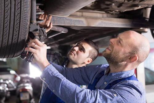 Two,professional,car,mechanics,checking,up,pressure,in,tires,at